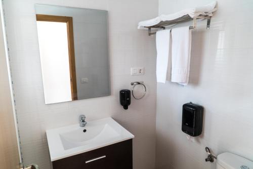 Baño blanco con lavabo y espejo en Pensión La Ola, en Grao de Castellón