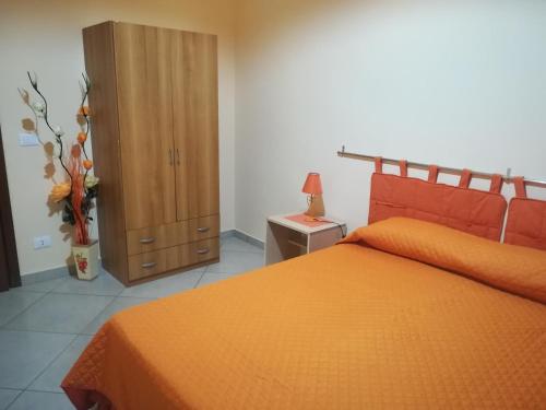 a bedroom with an orange bed and a wooden cabinet at B&B Il Gabbiano in Reggio Calabria