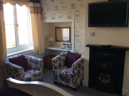 a living room with two chairs and a television at Highfield Guest House in Sheringham