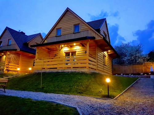 a wooden house with lights on the side of it at Domki pod Kuźnią in Falsztyn