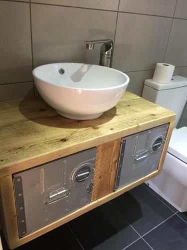 a bathroom with a bowl sink on a wooden counter at The Sail Loft - Hayling Island in South Hayling