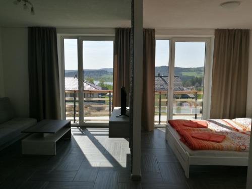 a bedroom with a bed and a large window at Apartmany 154 in Lipno nad Vltavou