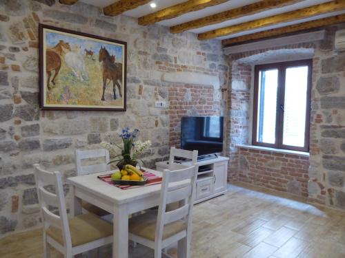 a dining room with a table and chairs and a television at Apartments Đukić in Kotor
