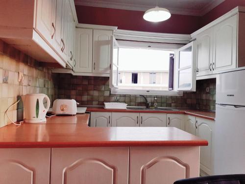 eine Küche mit weißen Schränken und einer roten Arbeitsplatte in der Unterkunft Mojo modern apartment in Alikanas