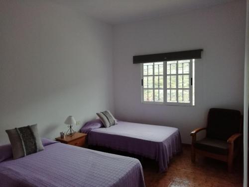 La GalgaにあるCasa Victoriaのベッド2台、椅子、窓が備わる客室です。