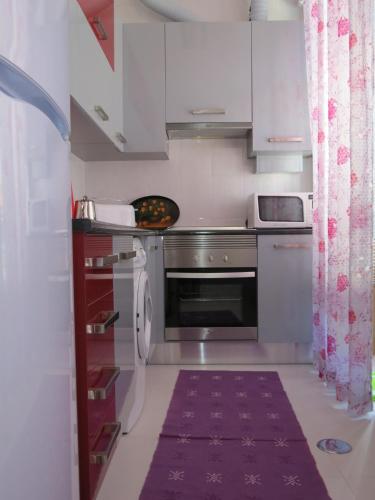 a kitchen with white cabinets and a purple rug at Alojamento Cesarini in Montijo