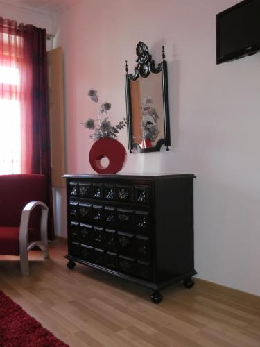 a black dresser with a mirror on a wall at Alojamento Cesarini in Montijo