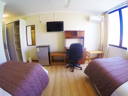 a room with two beds and a desk with a computer at Hotel San Francisco De la Selva in Copiapó