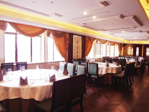 a dining room with tables and chairs and windows at Seventh Heaven Hotel in Shanghai