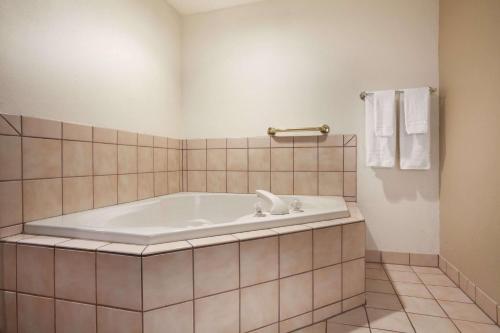 a large tub in a bathroom with a tiled floor at Super 8 by Wyndham Williston ND in Williston