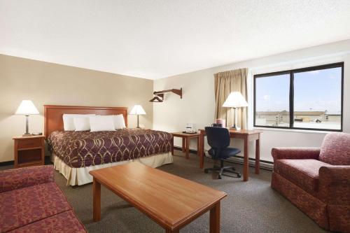 a hotel room with a bed and a desk and a couch at Super 8 by Wyndham Williston ND in Williston