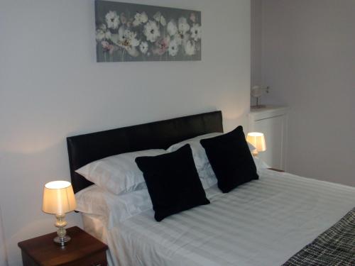 a bedroom with a bed with two black pillows at Lockinbar Holiday Apartments in Tenby