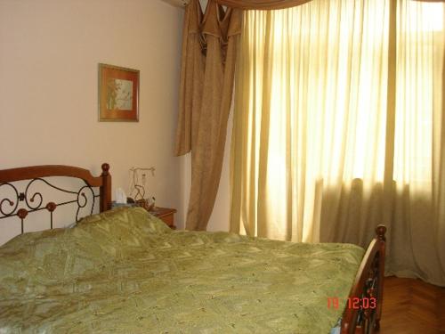 a bedroom with a green bed and a window at Sahil Apartment in Baku