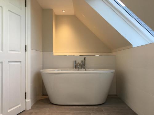 a white bath tub in a bathroom with a skylight at Dunvegan Castle Keepers Cottage in Dunvegan