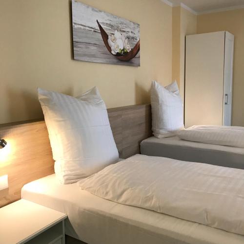 a bedroom with two beds with white pillows and a mirror at Hotel Select Suites & Aparts in Mönchengladbach