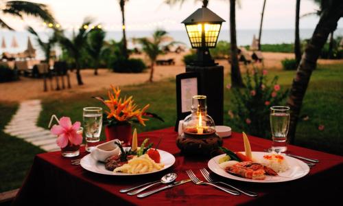 a table with plates of food on a red table cloth at Andamania Beach Resort, Khaolak - SHA plus in Khao Lak