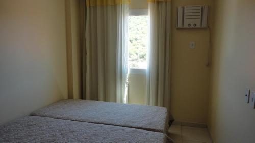 Habitación pequeña con cama y ventana en Prainha Lindo Apto com 02 quartos e 02 vagas de garagem, en Arraial do Cabo
