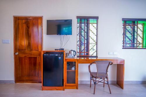 a room with a desk with a television and a chair at Sunrise Club Hotel in Negril
