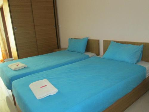 two beds with blue sheets in a room at The Ocean Residence in Nakhon Ratchasima