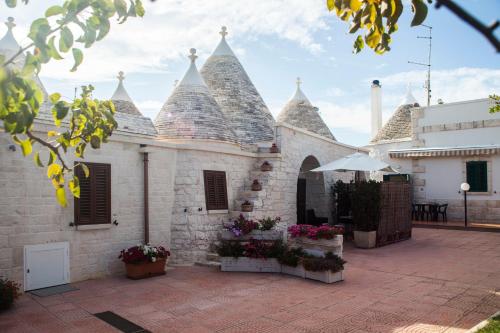 a white building with a roof with some flowers at Il Calàscione Apulian Villas in Locorotondo