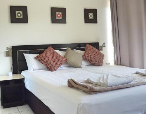 a bed with a white comforter and pillows at Jadran Motel & El Jays Holiday Lodge in Gold Coast