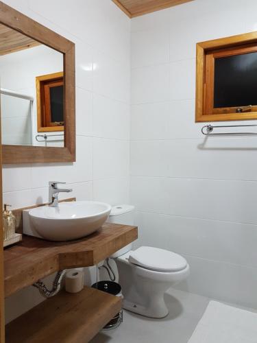 a bathroom with a sink and a toilet and a mirror at Pousada Vila dos Butias in Urubici