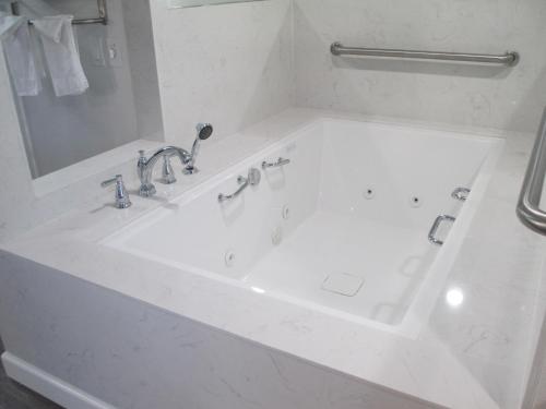 a white bathroom with a bath tub with a mirror at Claremont Lodge in Claremont