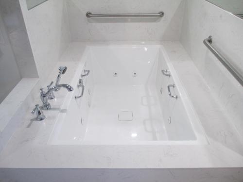 a white bath tub with faucets in a bathroom at Claremont Lodge in Claremont