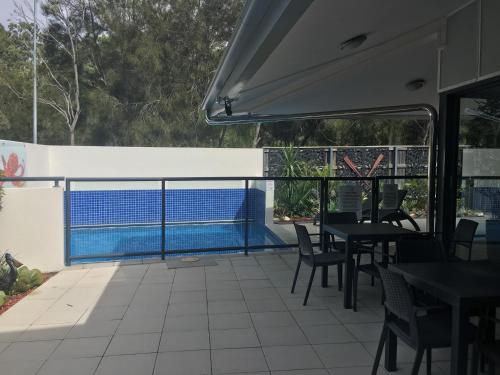 a patio with tables and chairs and a swimming pool at Manly Marina Cove Motel in Brisbane