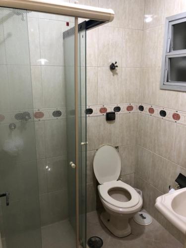 a bathroom with a toilet and a shower and a sink at Guarujá Enseada in Guarujá