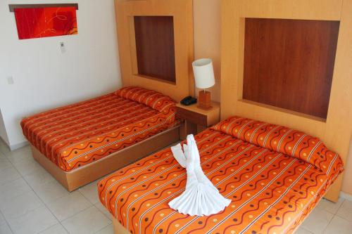 a hotel room with two beds with white dresses on them at Hotel Real Zapopan in Guadalajara