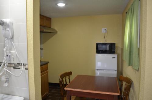 a kitchen with a table and a microwave on top of a refrigerator at Budget Inn Williamsville in Williamsville