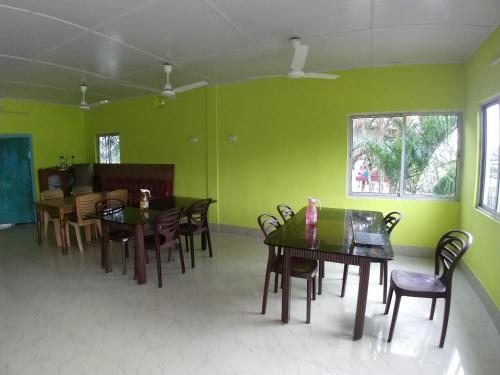 a dining room with green walls and wooden tables and chairs at Gorumara Nature's Cottage (A Unit Of M/S Ecological & Tours) in Jalpāiguri