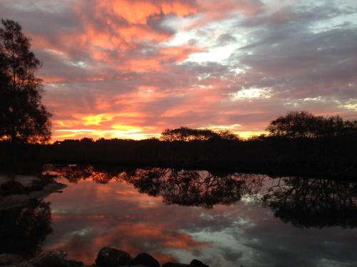a sunset over a river with a reflection in the water at Lani's Holiday Island in Forster