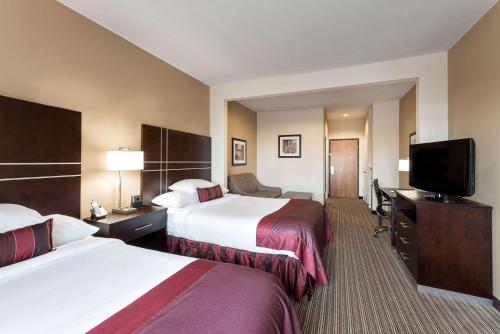 a hotel room with two beds and a flat screen tv at Wingate By Wyndham Houston / Willowbrook in Houston