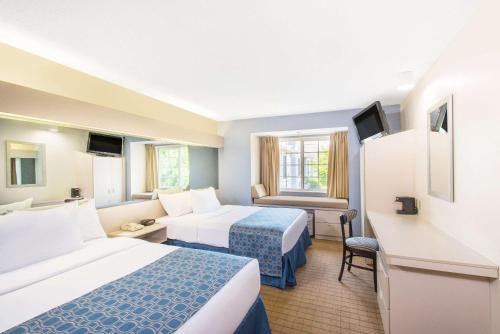 a hotel room with two beds and a desk at Microtel Inn & Suites by Wyndham in Seneca Falls