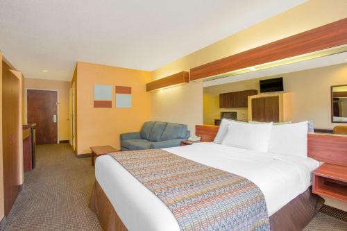 a hotel room with a large bed and a blue chair at Microtel Inn & Suites by Wyndham Kannapolis/Concord in Kannapolis