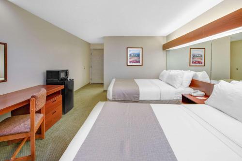 a hotel room with two beds and a desk at Microtel Inn & Suites by Wyndham Hattiesburg in Hattiesburg