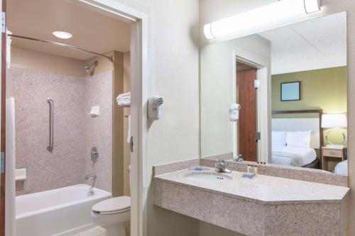 a bathroom with a sink and a toilet and a mirror at Hawthorn Suites Midwest City in Midwest City