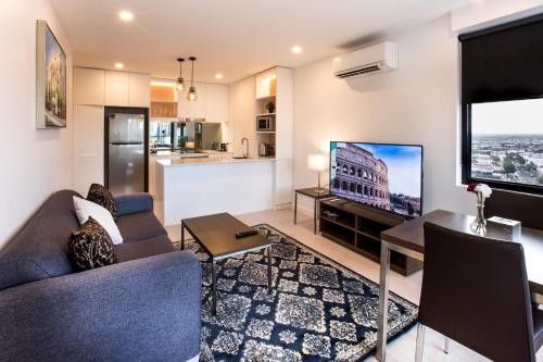a living room with a couch and a table with a tv at Spencer Street Apartments in Melbourne