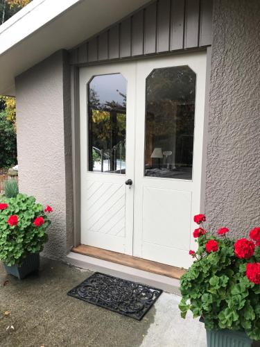 a white door on a house with red flowers at McIvor Lodge in Invercargill