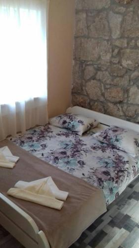a bed in a room with a stone wall at Apartment Nada in Rogoznica