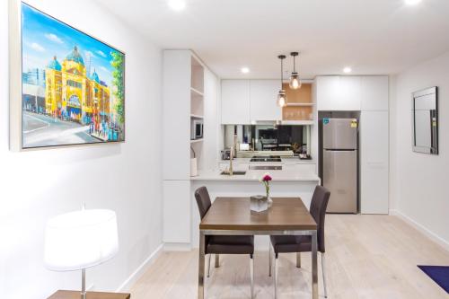 a kitchen with a table and a refrigerator at Spencer Street Apartments in Melbourne