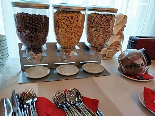 three vases filled with food on a table with silverware at Hotel Vadászkürt Superior in Székesfehérvár