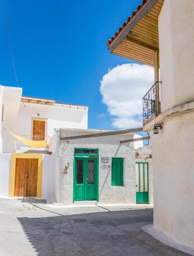 a white house with green doors on a street at Private studio in historic house in Lástros