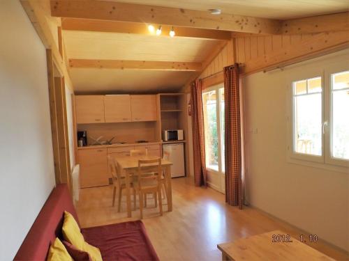 ein Wohnzimmer mit einem Tisch und einer Küche in der Unterkunft Les chalets du Relais d'Aguilar in Tuchan