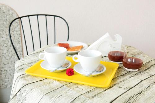 a table with two cups and a tray with food at Addisa Locazione Breve in Castellammare del Golfo