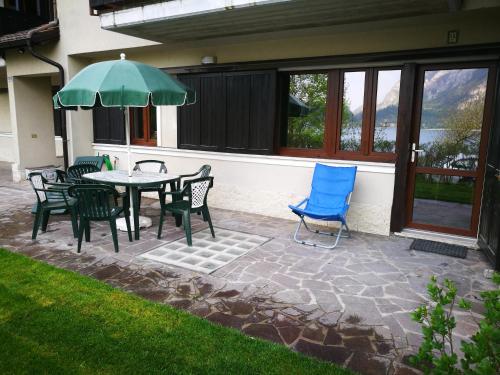 a patio with a table and chairs and an umbrella at Appartamento Chiara in Ledro