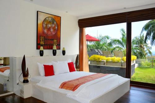 a bedroom with a white bed and a large window at Villa Tiara in Senggigi