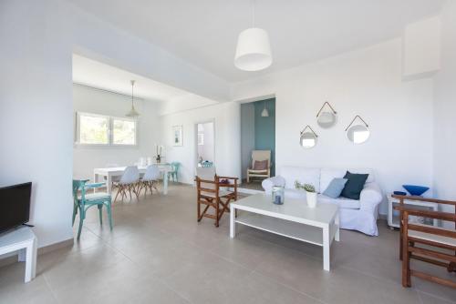 een woonkamer met een witte bank en tafels en stoelen bij Vourvourou Sea View in Vourvourou